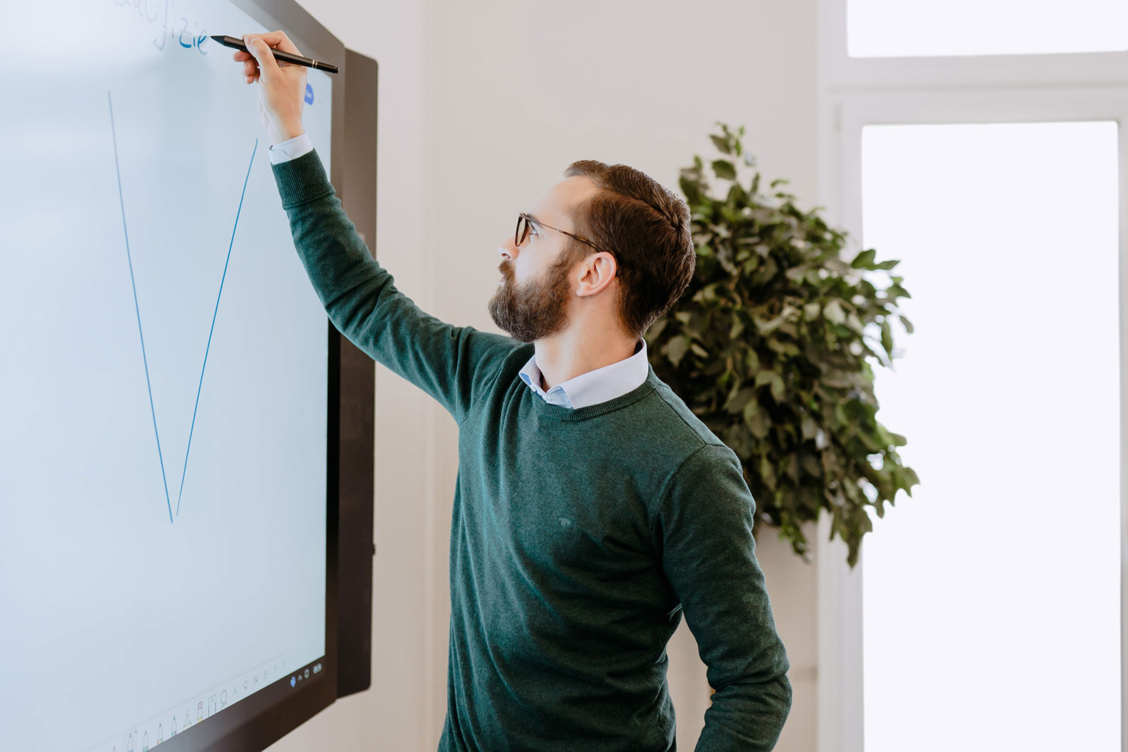 Mitarbeiter zeichnet etwas auf einem Smartboard