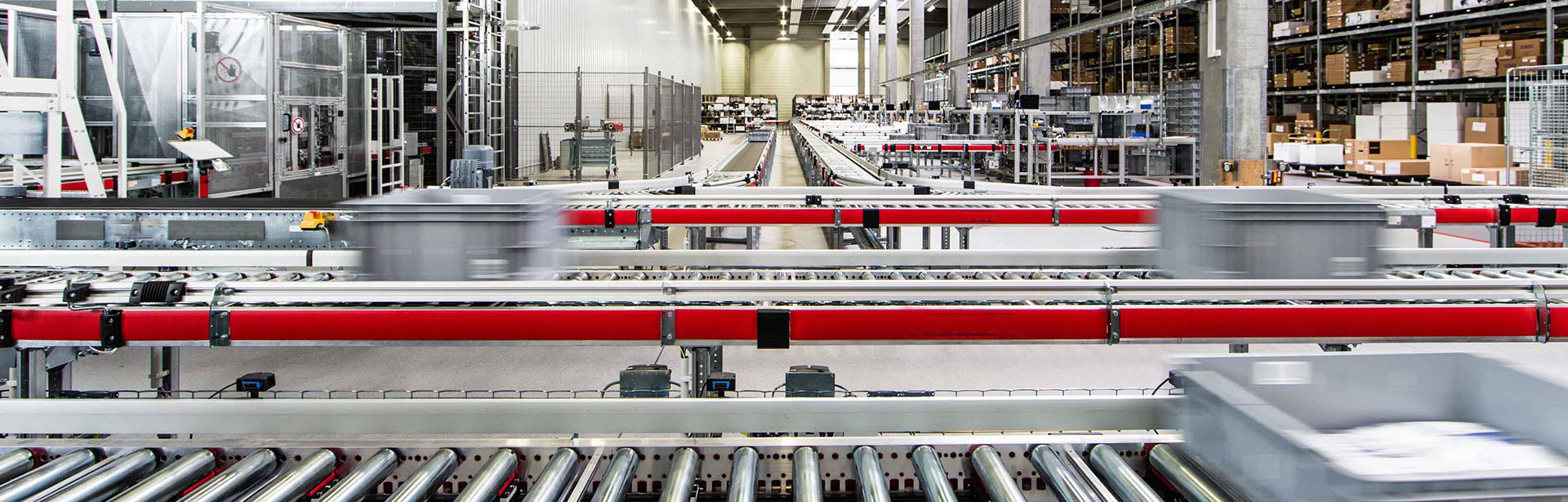 Nahaufnahme von Laufbändern mit Kisten in einer Logistikhalle