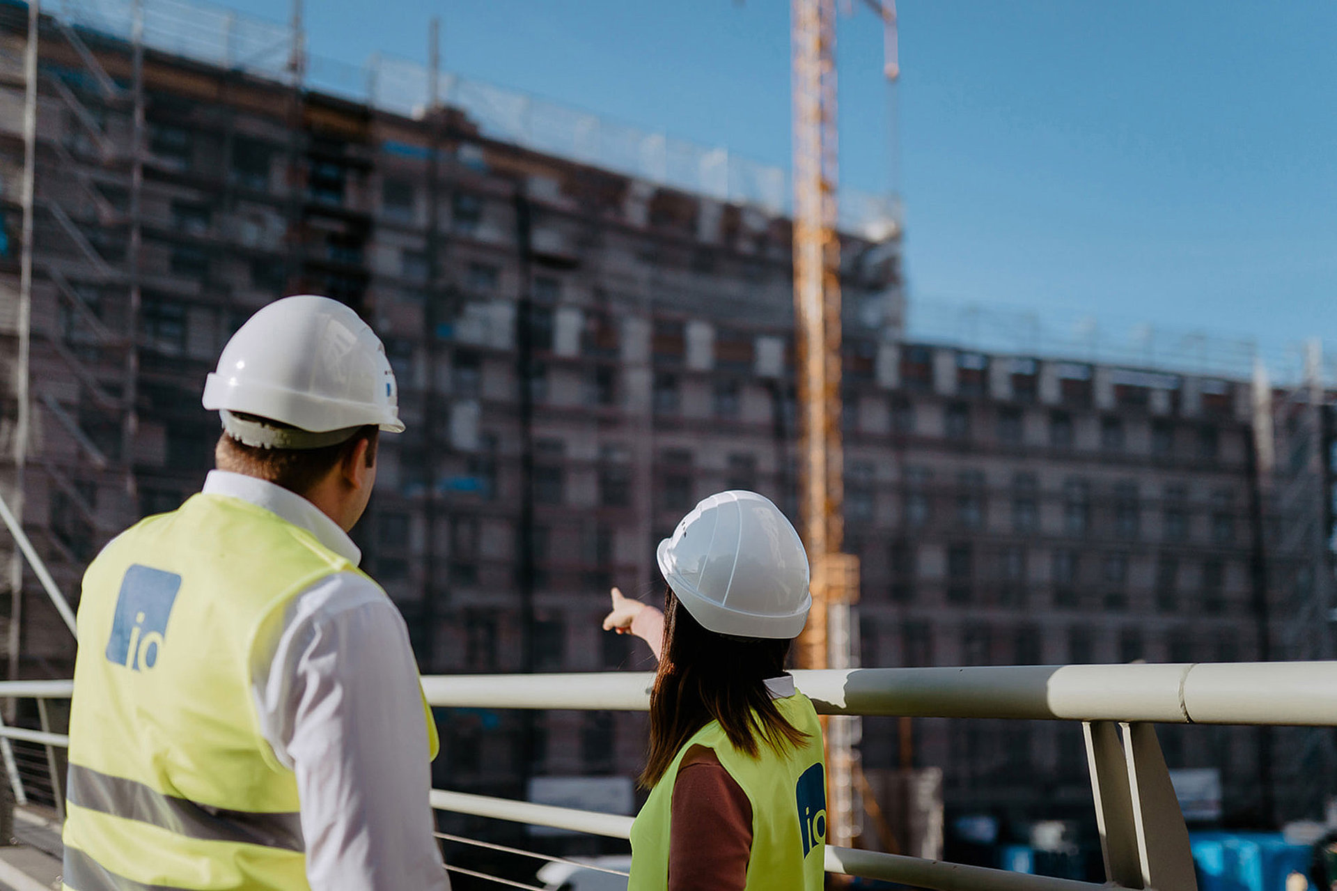 Zwei Mitarbeiter von io mit Warnwesten und Helmen auf einer Baustelle 