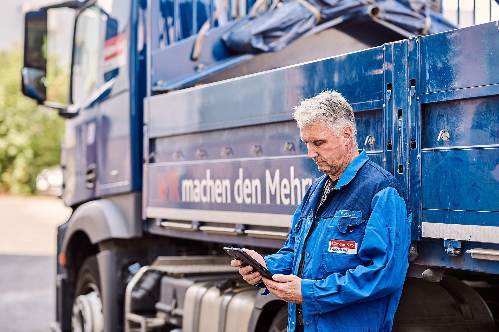 Mann mit Tablet lehnt an LKW