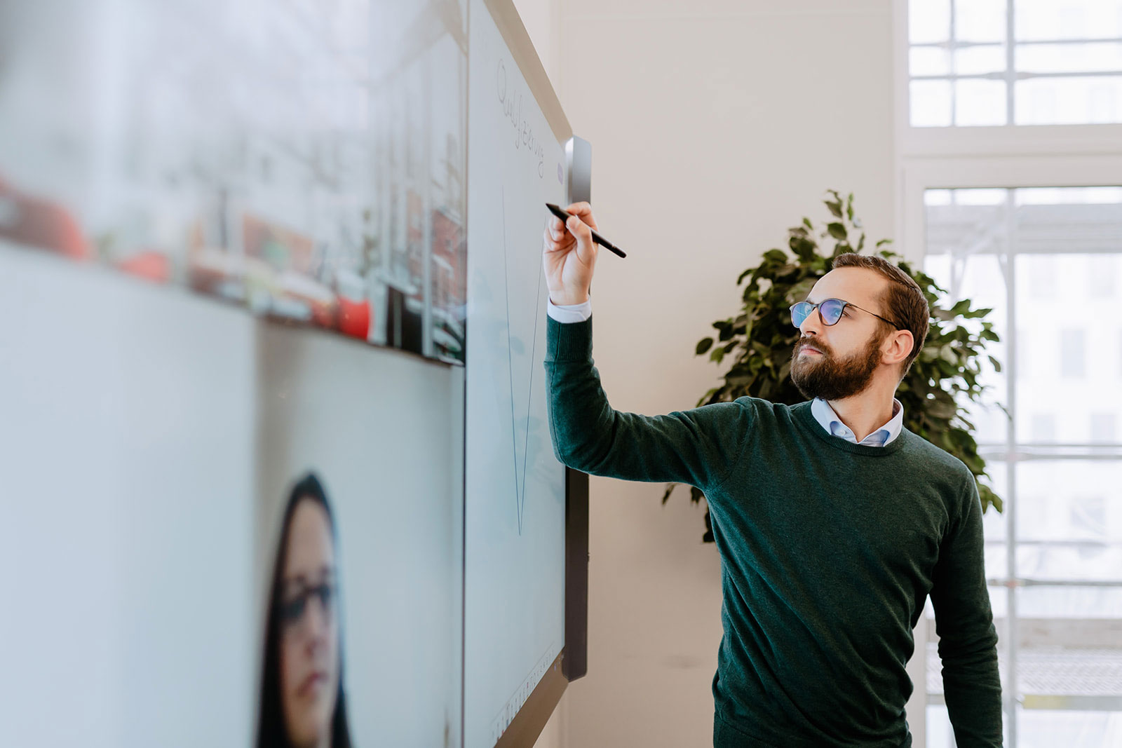 Ein Mann schreibt etwas an ein Smartboard.